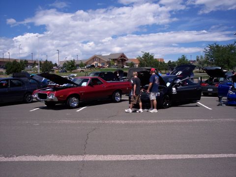 1972 Ford Ranchero - Red 1972 Ford Ranchero at a car show with its hood up, surrounded by other vehicles.