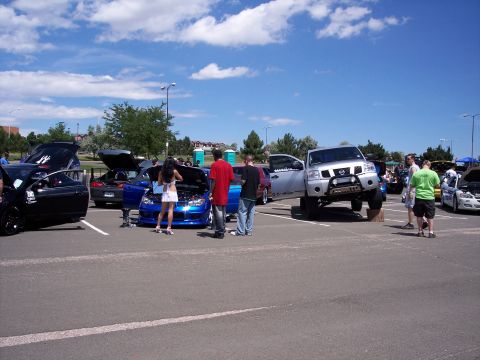 1972 Ford Ranchero - Several modified cars and a lifted truck are on display at an outdoor event under a partly cloudy sky.