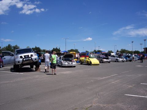 1972 Ford Ranchero - A lifted Nissan Titan pickup truck is displayed at an outdoor car show with other vehicles.