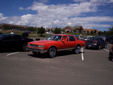 1972 Ford Ranchero - Orange sedan with chrome rims parked in a lot, likely a 1977 model.