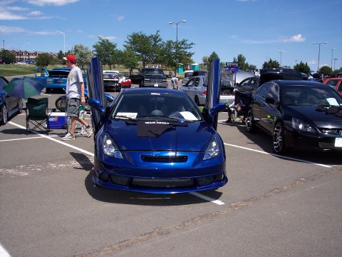 1972 Ford Ranchero - A blue coupe with its doors open is displayed at a car show, with other vehicles visible in the background.