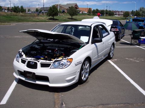 1972 Ford Ranchero - A white Subaru Impreza WRX STI is parked with its hood open, revealing the engine bay. An "STI" badge is visible on the front grille.
