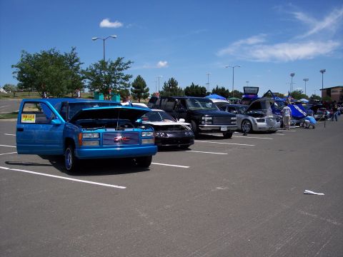 1972 Ford Ranchero - A row of vehicles are parked in a lot under a blue sky with scattered clouds.