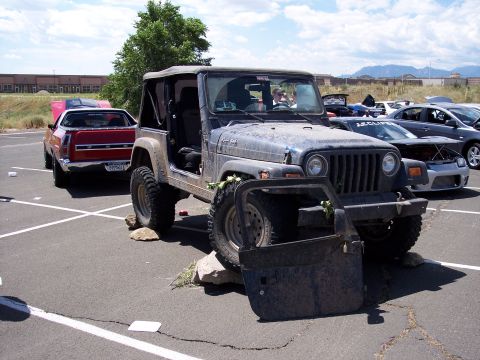 1972 Ford Ranchero - A weathered Jeep Wrangler is parked with its door off, resting on rocks in a parking lot.