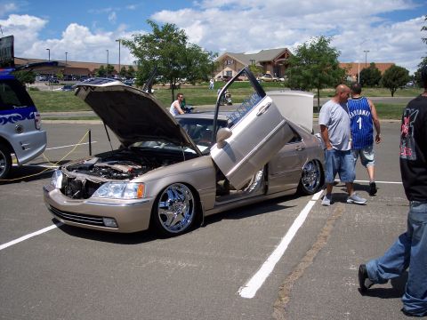1972 Ford Ranchero - A modified sedan with its hood and doors open is displayed at an outdoor event.