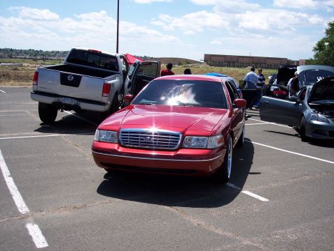 1972 Ford Ranchero - A red sedan is parked in a lot, with a pickup truck and another car visible nearby.