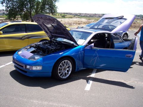 1972 Ford Ranchero - Customized blue sports car with open hood and door, parked at an outdoor event with another car nearby.