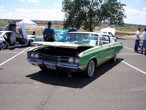 1972 Ford Ranchero - Green 1966 Dodge Charger displayed with its hood open at a car show event.