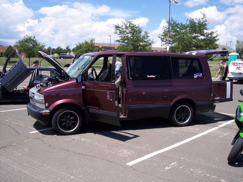 1972 Ford Ranchero - A maroon van with its doors and hood open is parked in a lot next to another car with gullwing doors.