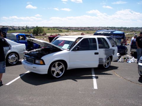 1972 Ford Ranchero - A white SUV is displayed with its hood and door open, parked at an outdoor event.