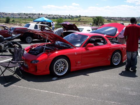 1972 Ford Ranchero - A red sports car, identified by its RX7 badging, is displayed with its hood open at an outdoor event.