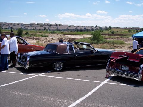 1972 Ford Ranchero - A black 1977 Cadillac Coupe de Ville convertible with a brown vinyl top is parked at an outdoor event.