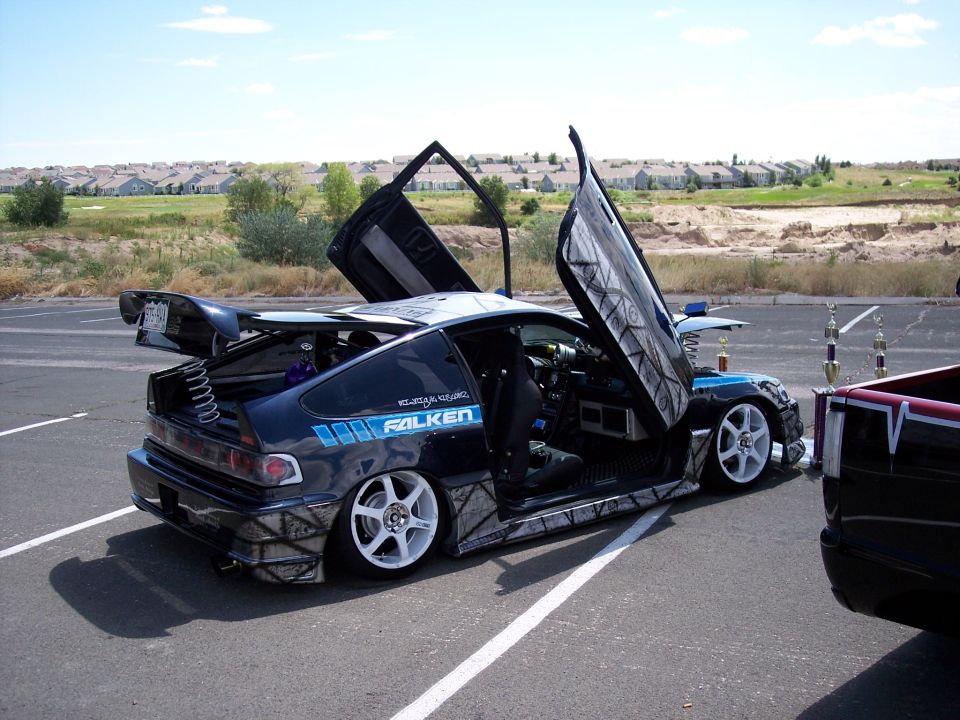 Custom Honda CRX with gullwing doors open, Falken tires, and a big spoiler. Another vehicle is parked next to it