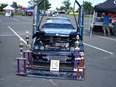 1972 Ford Ranchero - A modified coupe with butterfly doors and an exposed engine sits on display with several trophies.