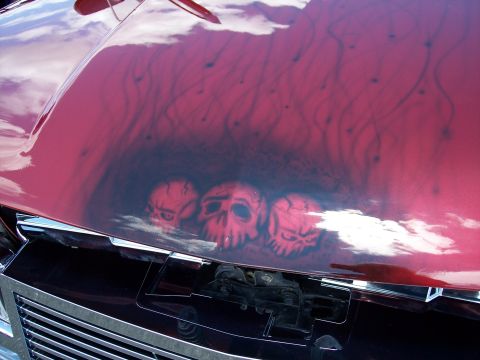 1972 Ford Ranchero - Airbrushed skulls and flames adorn the hood of a car, which is open to reveal the engine bay.