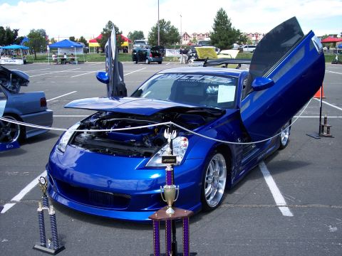 1972 Ford Ranchero - A modified blue sports car with custom doors is displayed at an outdoor event.