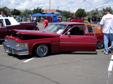 1972 Ford Ranchero - A red Cadillac sedan is displayed with its hood and driver door open at an outdoor car show.