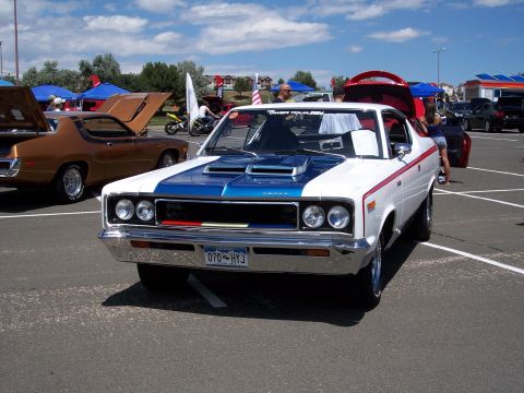 1972 Ford Ranchero - A white and blue coupe with red racing stripes and hood scoops is parked at an outdoor event.