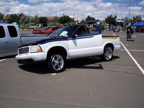 1972 Ford Ranchero - A customized pickup truck is displayed at an outdoor car show with other vehicles and people around.