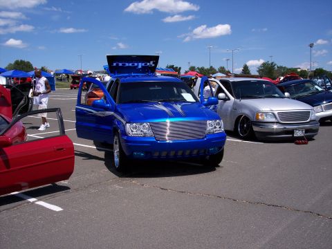 1972 Ford Ranchero - Several vehicles are parked in a lot under a blue sky with scattered clouds.