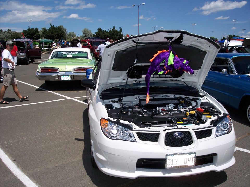 White Subaru Impreza WRX front view, hood open, purple dragon toy hanging