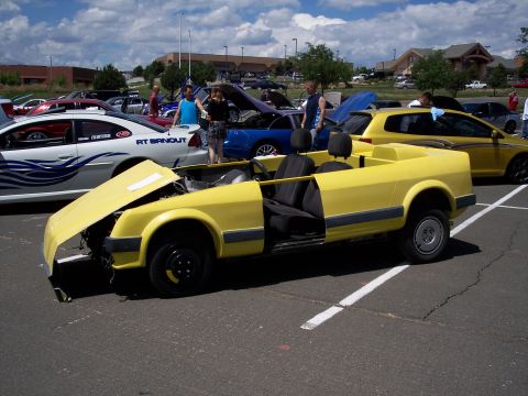 1972 Ford Ranchero - A yellow custom convertible with its hood open sits in a parking lot at a car show.