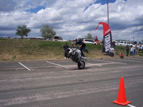 1972 Ford Ranchero - A motorcyclist performs a wheelie during an event, with onlookers gathered on a grassy embankment.