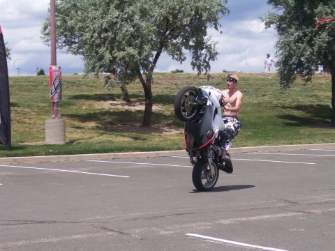 1972 Ford Ranchero - A man performs a wheelie on a motorcycle in an empty parking lot on a cloudy day.