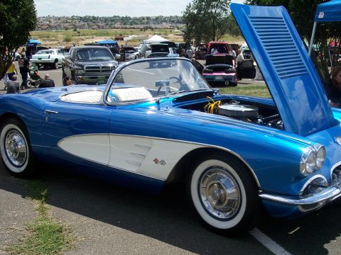 1972 Ford Ranchero - A classic blue and white 1958 Chevrolet Corvette convertible is displayed with its hood open at an outdoor car show.