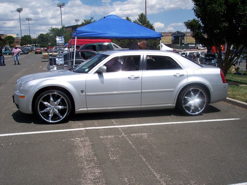 Silver sedan with large chrome rims parked on asphalt