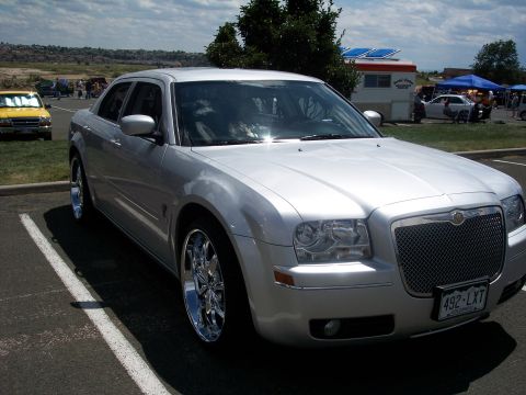 1972 Ford Ranchero - Silver Chrysler 300 sedan with custom chrome wheels parked at an outdoor event.