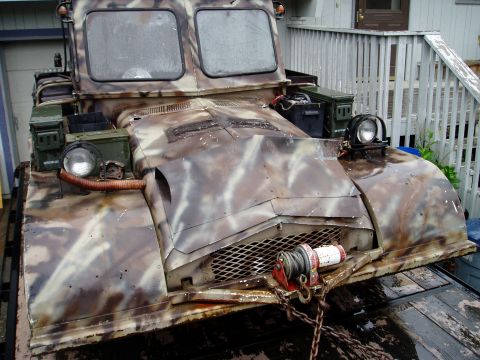 2000 Ford E350 - This heavily modified tracked vehicle is loaded onto a trailer, its camouflage paint job and winch suggesting a specialized purpose.