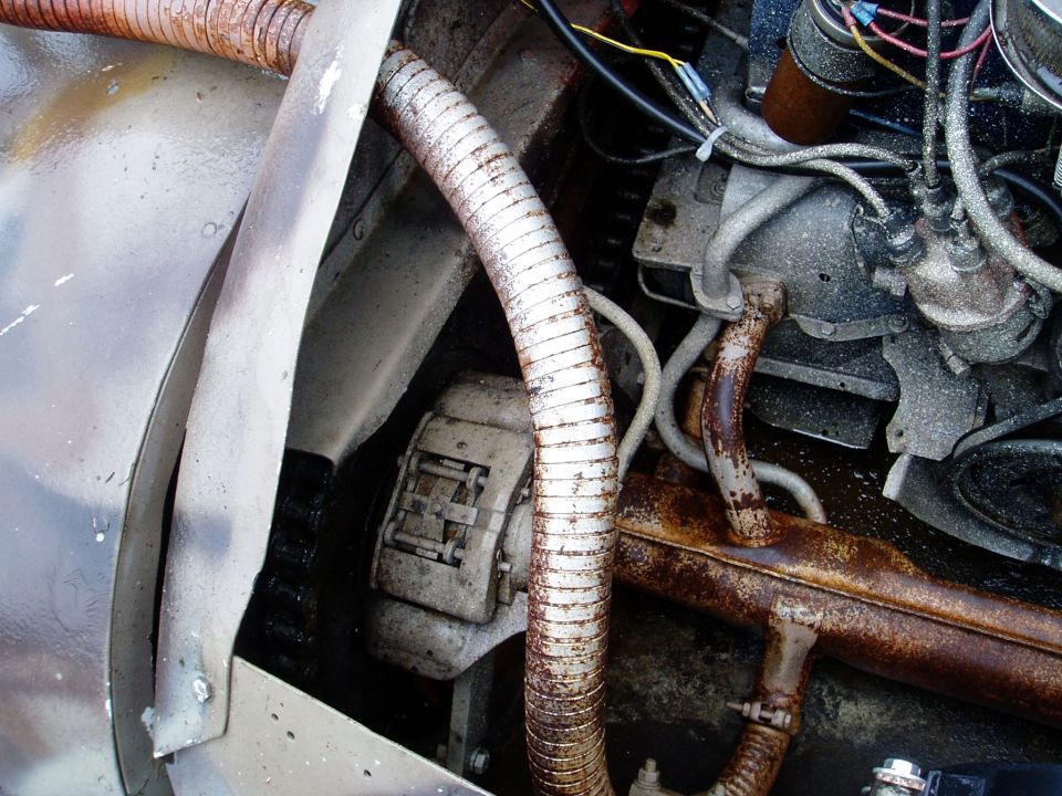 Close-up of engine parts including hoses, wiring, and exhaust