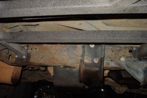 1993 Ford Bronco - Close-up view of the underbody frame and suspension components, showing signs of rust and bolted connections.