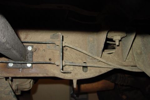 1993 Ford Bronco - Close-up view of the rusty undercarriage of a vehicle, revealing brake lines and suspension parts.