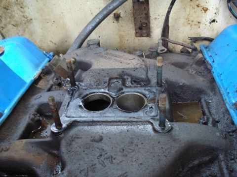 1967 Ford F-250 - Close-up of a greasy engine intake manifold with visible bolts and blue valve covers.