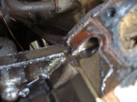 1967 Ford F-250 - A close-up view of a greasy engine part, possibly a gasket or manifold, with metal pipes visible in the background.