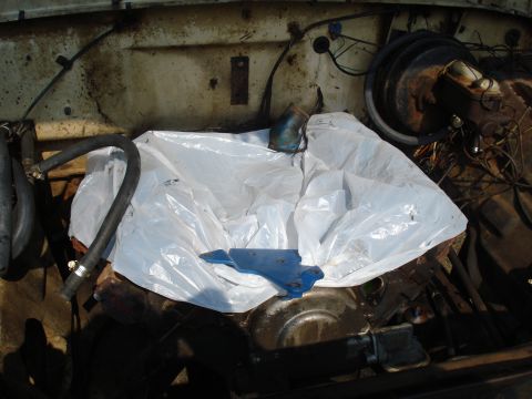 1967 Ford F-250 - The engine bay of a vehicle, partially covered with a white tarp, showing the brake booster and master cylinder.