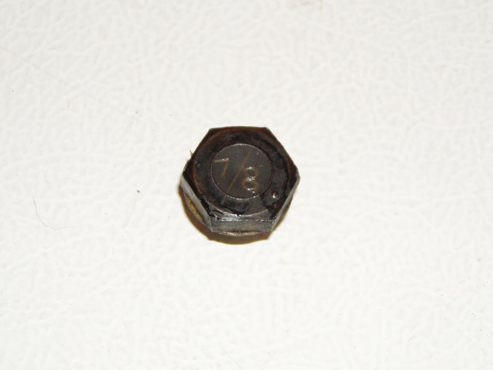 Black hex bolt head stamped 7/8 on a white textured surface