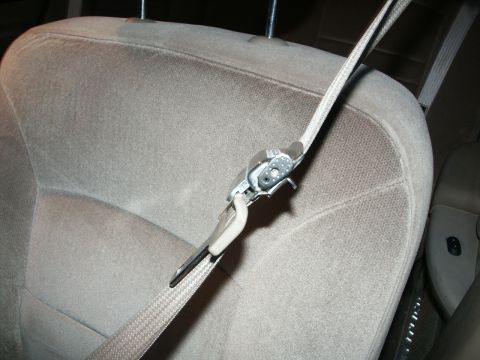 2001 Mercury Grand Marquis - The seatbelt mechanism and strap are visible against the tan fabric of a car seat.