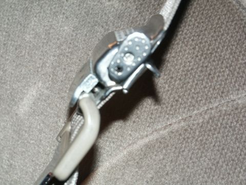 2001 Mercury Grand Marquis - Close-up of a seatbelt buckle mechanism, showing the metal latch and plastic components against a textured gray fabric background.
