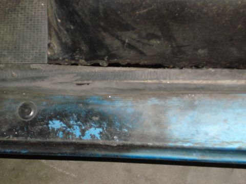 1979 Chevrolet C/K Pickup - Close-up of a worn blue truck door sill with a black rubber seal and a screw.