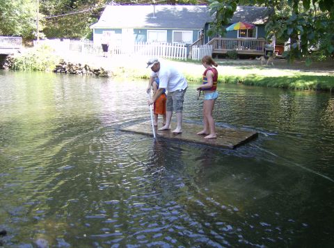 1986 Ford Bronco - Family enjoys a day on the water, floating on a raft near a house.
