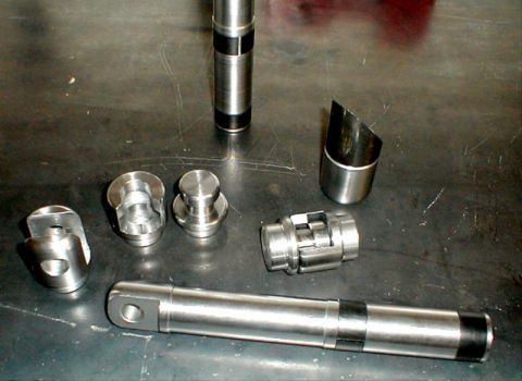 1996 Ford Bronco - Various metal parts are arranged on a metallic surface, possibly for assembly or repair.
