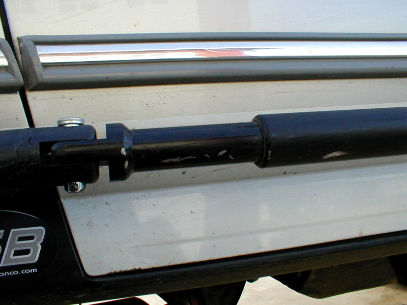 Close-up of black accessory attached to white vehicle side trim with chrome accent