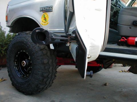 1996 Ford Bronco - The slider door mechanism is visible on this 1996 Ford Bronco, alongside a large off-road tire and a fire extinguisher inside.