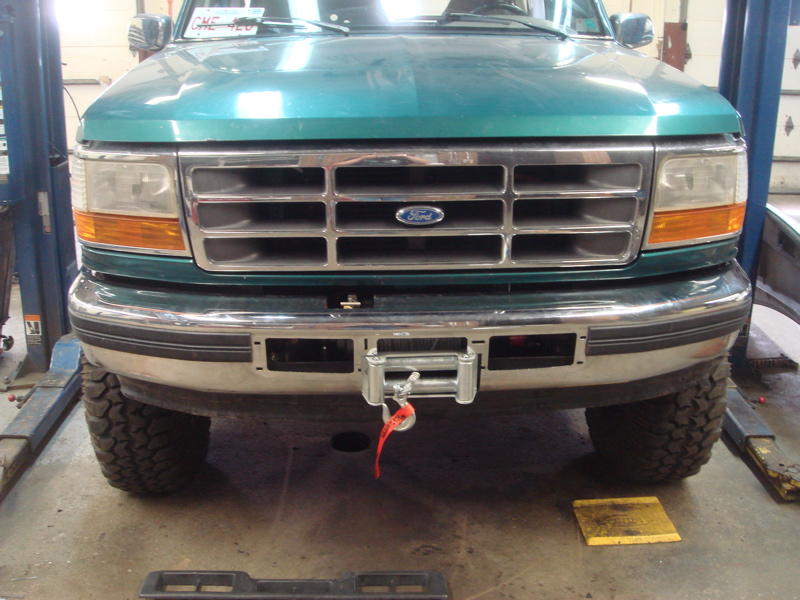 Front view of green Ford truck with a winch mounted on the bumper. License plate visible