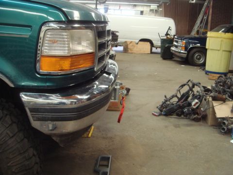 1996 Ford Bronco - Front view of a green Ford truck in a garage, with a tow strap attached to the bumper.