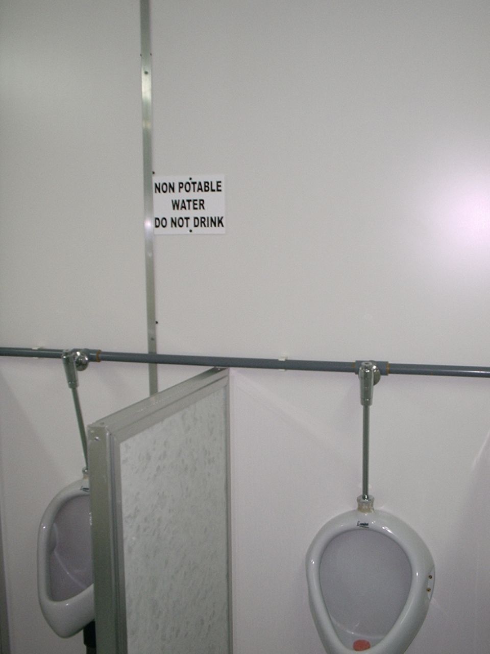 Urinals with a sign reading 'NON POTABLE WATER DO NOT DRINK'