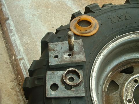 1995 Ford Bronco - Metal spacers and a bolt are laid out on a tire, likely for a vehicle modification.
